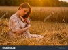 pregnant-woman-in-a-wheat-field-a-woman-posing-sitting-on-a-freshly-mown-straw312292199.jpg